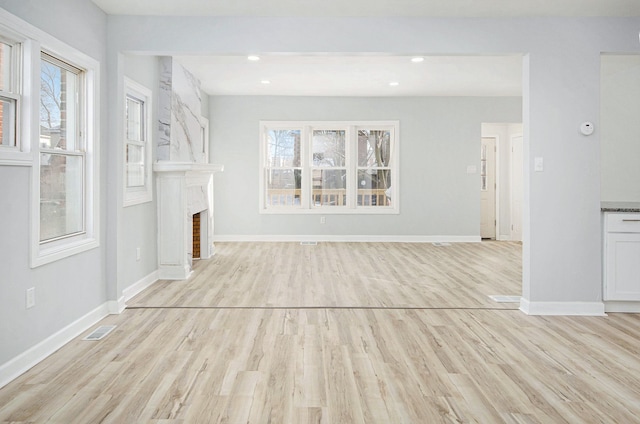 unfurnished living room with a healthy amount of sunlight, a fireplace, and light hardwood / wood-style flooring