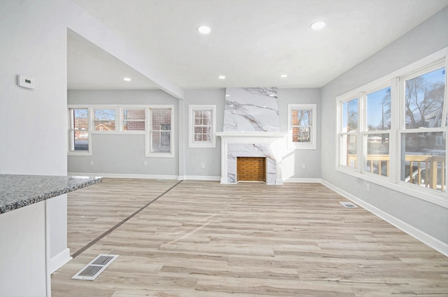 unfurnished living room with a wealth of natural light, light wood-type flooring, and a premium fireplace