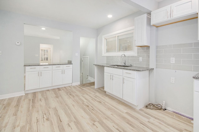 kitchen featuring white cabinets, light wood-type flooring, sink, and stone countertops