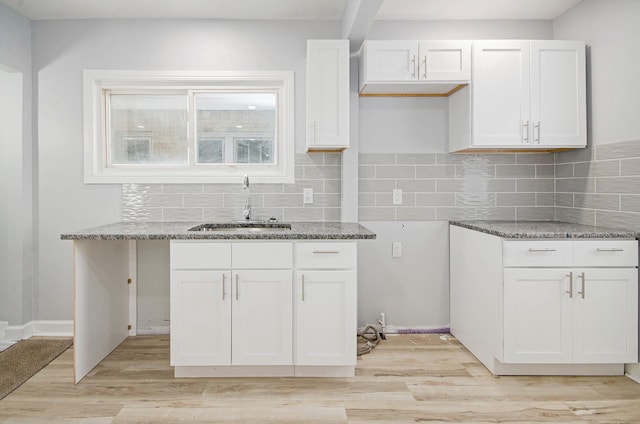 kitchen featuring sink, stone countertops, white cabinets, and light wood-type flooring