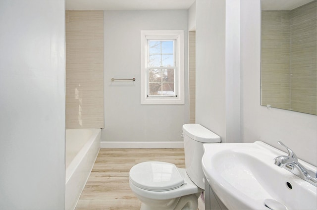 bathroom featuring sink, hardwood / wood-style floors, toilet, and a washtub