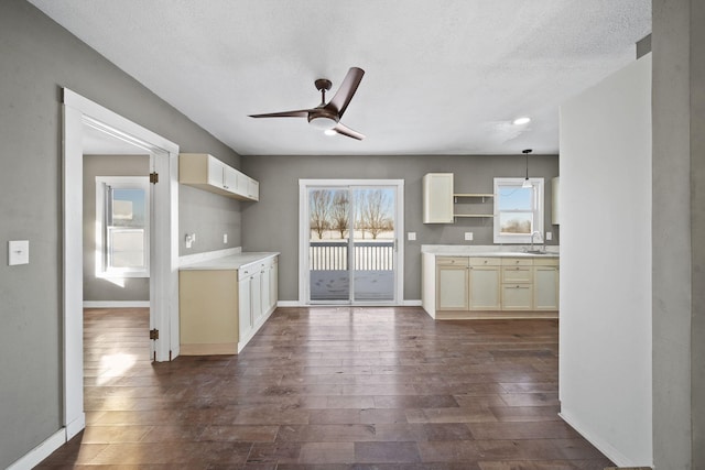 kitchen with dark wood-type flooring, a textured ceiling, decorative light fixtures, ceiling fan, and sink