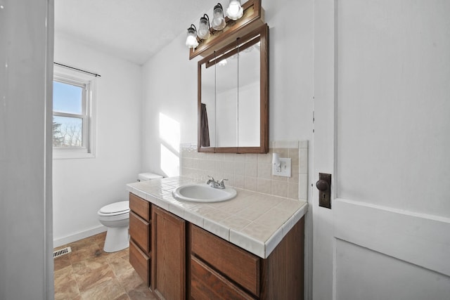 bathroom with decorative backsplash, vanity, and toilet