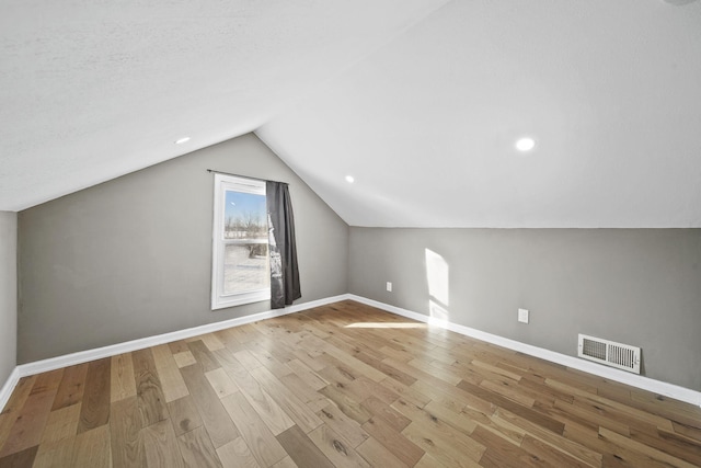 bonus room featuring a textured ceiling, light hardwood / wood-style flooring, and lofted ceiling