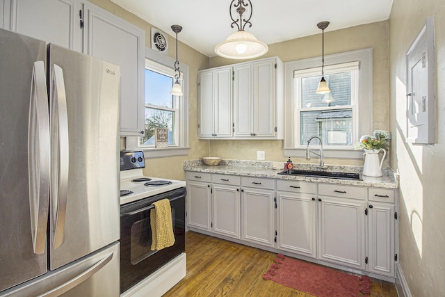 kitchen featuring decorative light fixtures, sink, white cabinetry, range with electric cooktop, and stainless steel fridge