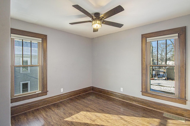 empty room with ceiling fan, plenty of natural light, and dark hardwood / wood-style floors