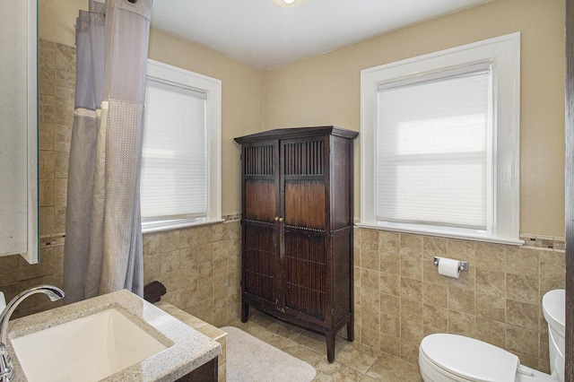 bathroom with toilet, tile walls, tile patterned floors, and vanity