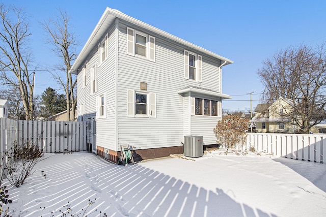 snow covered rear of property featuring cooling unit