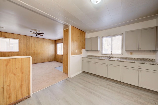 kitchen featuring wood walls, gray cabinets, ceiling fan, sink, and light hardwood / wood-style flooring