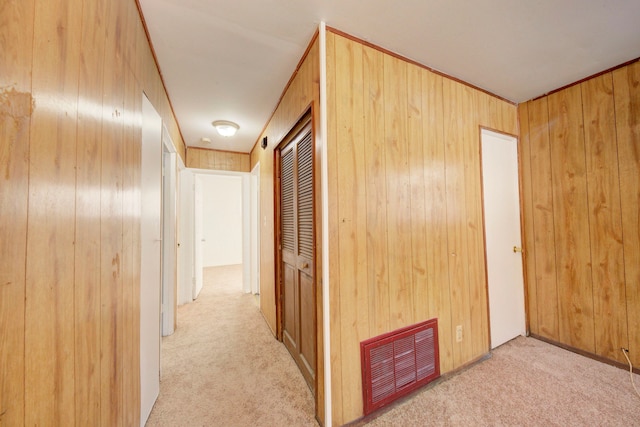 hall featuring wooden walls and light carpet