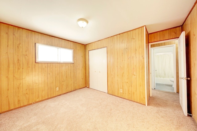 unfurnished bedroom featuring a closet, wood walls, and light colored carpet