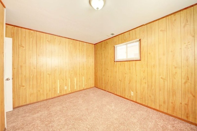 empty room featuring wood walls and light carpet