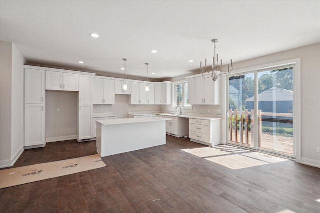 kitchen featuring a kitchen island, white cabinets, pendant lighting, and dark hardwood / wood-style floors