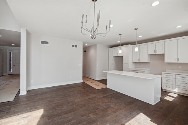 kitchen with white cabinets, a kitchen island, a chandelier, pendant lighting, and dark wood-type flooring