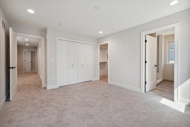 unfurnished bedroom featuring light carpet, a closet, and connected bathroom