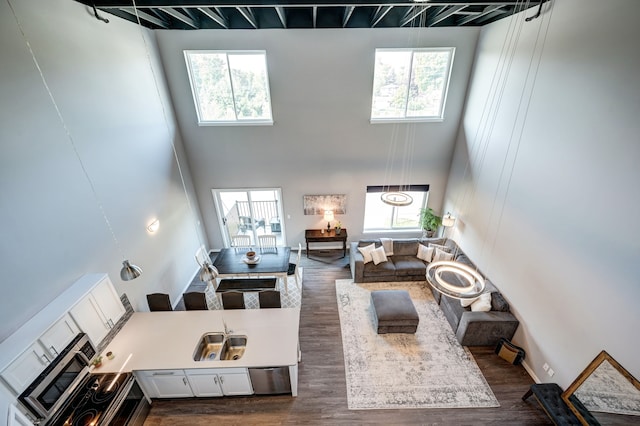 living room with a towering ceiling and dark wood-style flooring