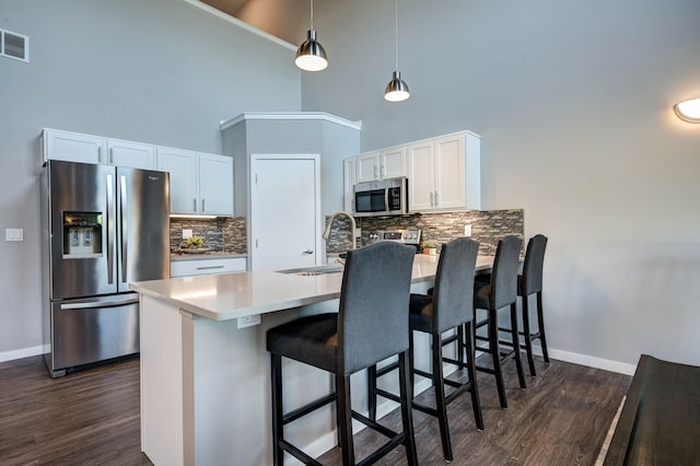 kitchen featuring appliances with stainless steel finishes, white cabinetry, dark wood-type flooring, and a peninsula