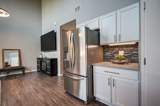 kitchen featuring visible vents, dark wood finished floors, decorative backsplash, white cabinets, and stainless steel refrigerator with ice dispenser