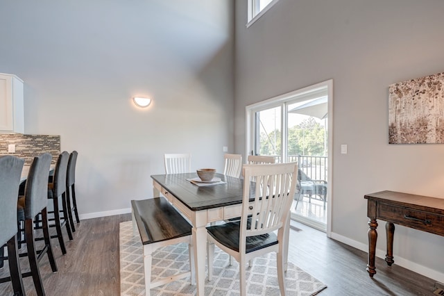 dining area with wood finished floors, baseboards, and a towering ceiling