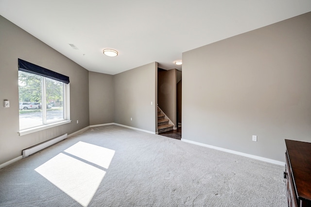 carpeted empty room with baseboard heating, visible vents, stairs, and baseboards