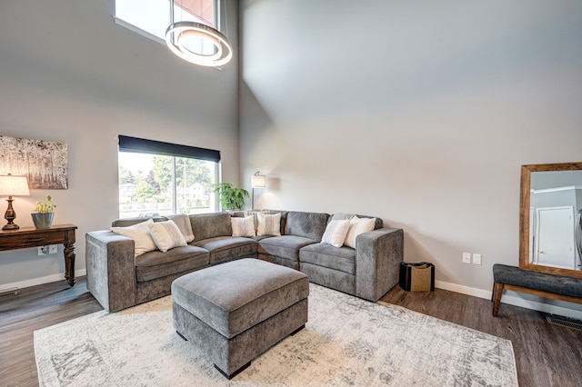 living area with baseboards, a high ceiling, and wood finished floors