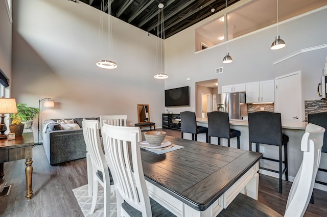 dining room with visible vents, a high ceiling, and wood finished floors