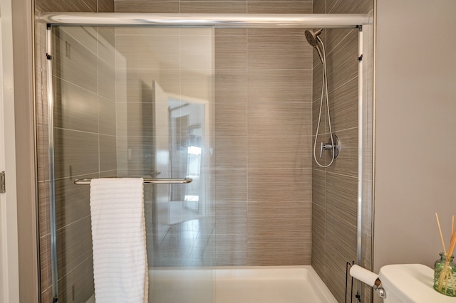 bathroom featuring toilet and a shower stall