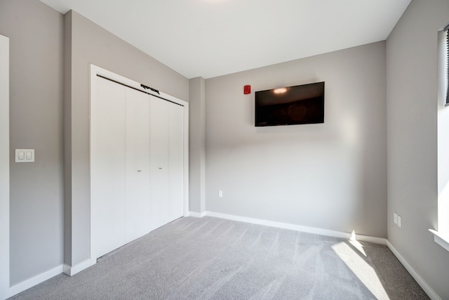 unfurnished bedroom with a closet, carpet flooring, and baseboards