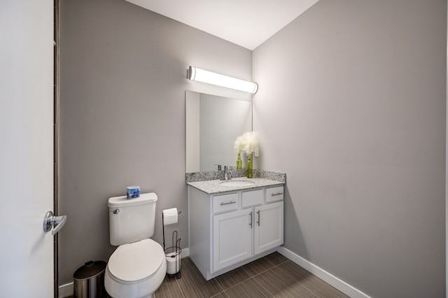 bathroom featuring vanity, toilet, and baseboards