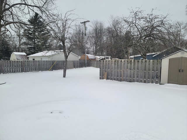 yard covered in snow featuring a storage shed