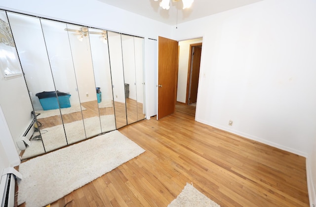 unfurnished bedroom featuring light wood-type flooring and a baseboard heating unit