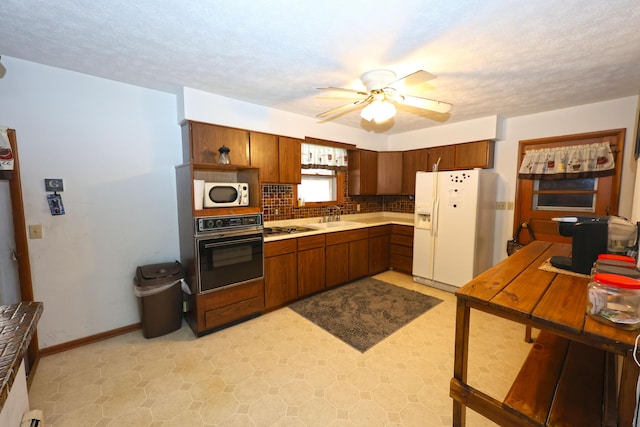 kitchen with a textured ceiling, black appliances, tasteful backsplash, ceiling fan, and sink