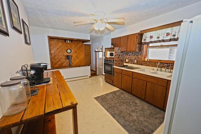 kitchen featuring black appliances, a textured ceiling, decorative backsplash, a baseboard heating unit, and sink