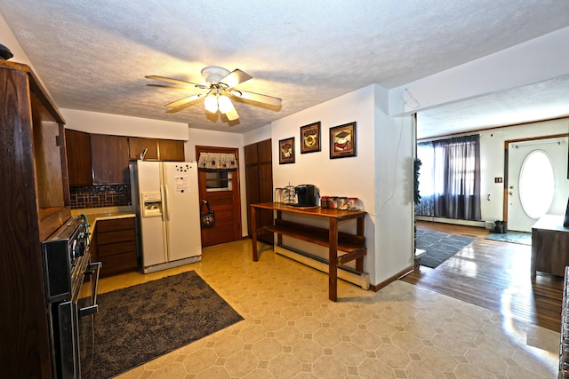 kitchen featuring a baseboard radiator, decorative backsplash, white fridge with ice dispenser, ceiling fan, and dark brown cabinets