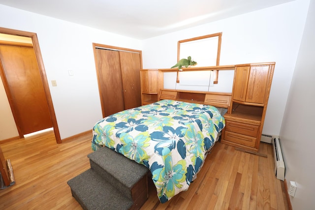 bedroom with light hardwood / wood-style floors, baseboard heating, and a closet