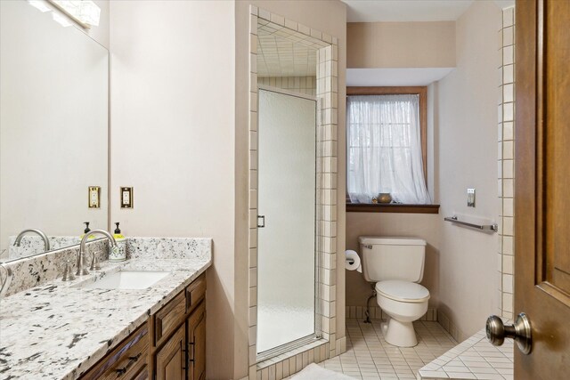 bathroom with tile patterned flooring, an enclosed shower, vanity, and toilet