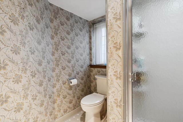 bathroom featuring toilet, walk in shower, and tile patterned floors