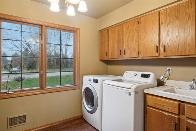 laundry room with dark wood-type flooring, washer and dryer, cabinets, and plenty of natural light