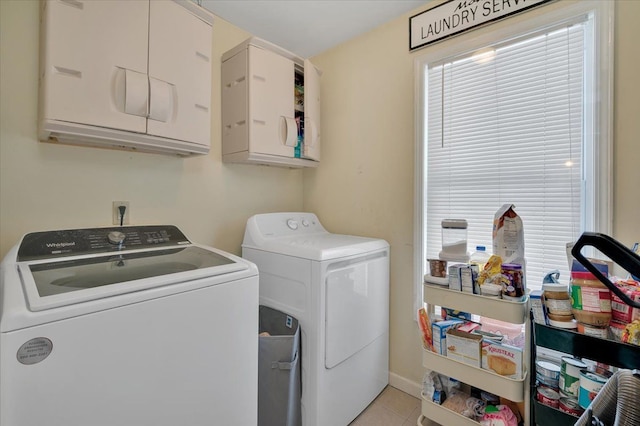 clothes washing area featuring washer and clothes dryer, light tile patterned flooring, and cabinets