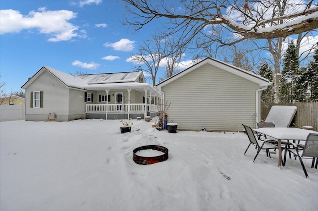 snow covered rear of property featuring a porch and an outdoor fire pit