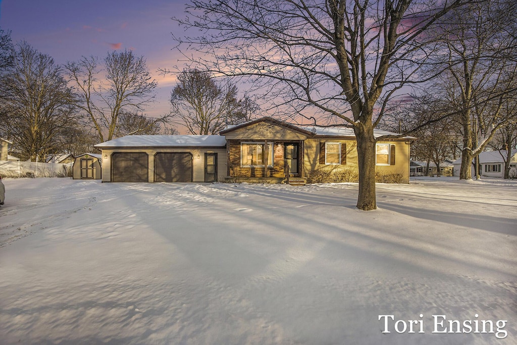 view of front of home with a garage and a storage shed