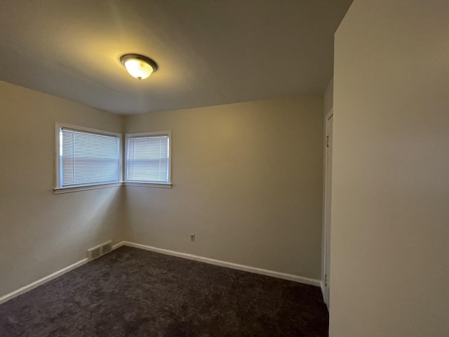 unfurnished room featuring dark carpet