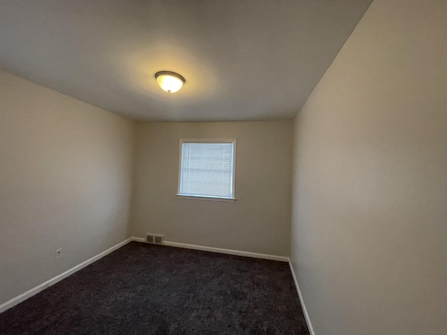 spare room featuring dark colored carpet