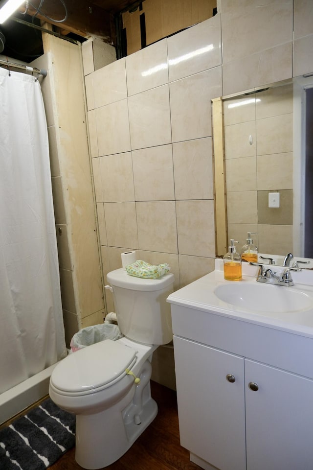 bathroom featuring tile walls, hardwood / wood-style floors, toilet, walk in shower, and vanity