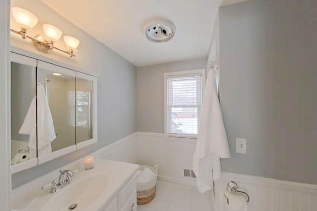 full bath featuring tile patterned floors, visible vents, vanity, and wainscoting