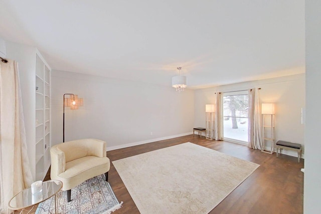 sitting room featuring a notable chandelier, baseboards, and dark wood-type flooring