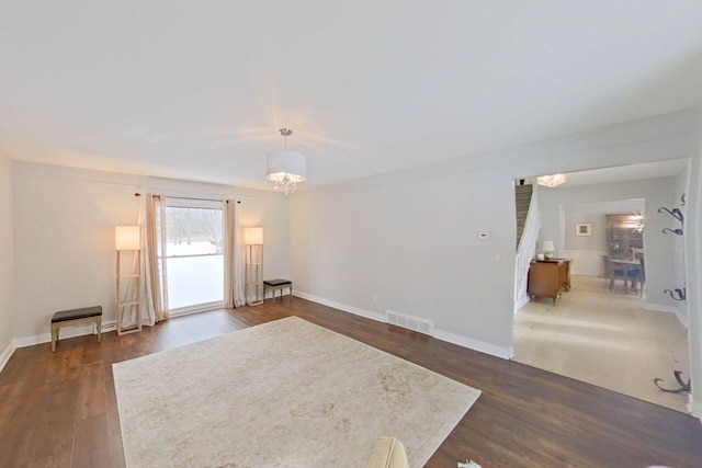 interior space featuring dark wood-style flooring, a chandelier, visible vents, and baseboards