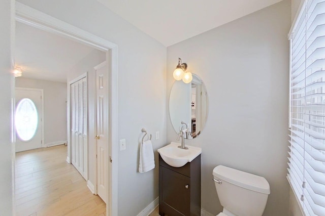 half bathroom featuring wood finished floors, toilet, and vanity