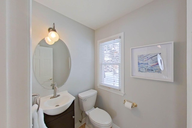 bathroom with toilet, baseboards, vanity, and plenty of natural light