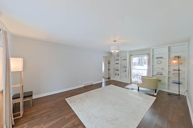 living room featuring dark wood finished floors, visible vents, an inviting chandelier, and baseboards
